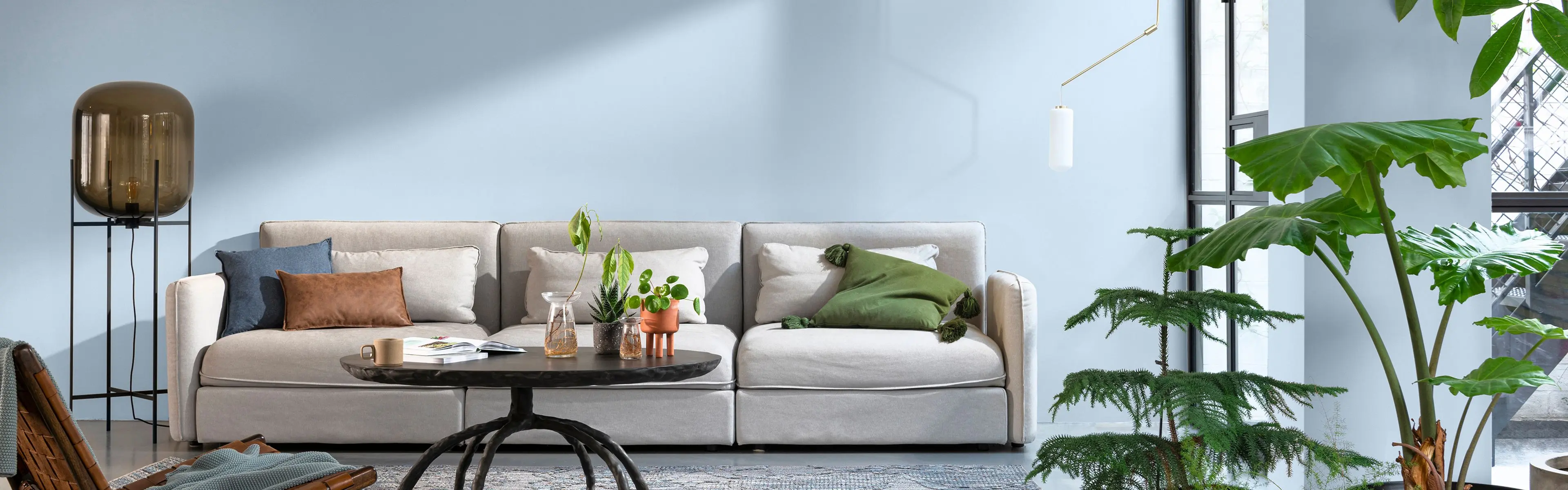moderne stue med blåmalte vegger og lysegrå sofa med puter