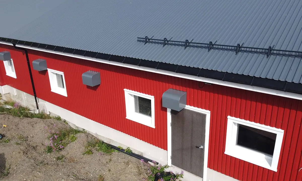 Rød driftsbygning med stålplater på taket