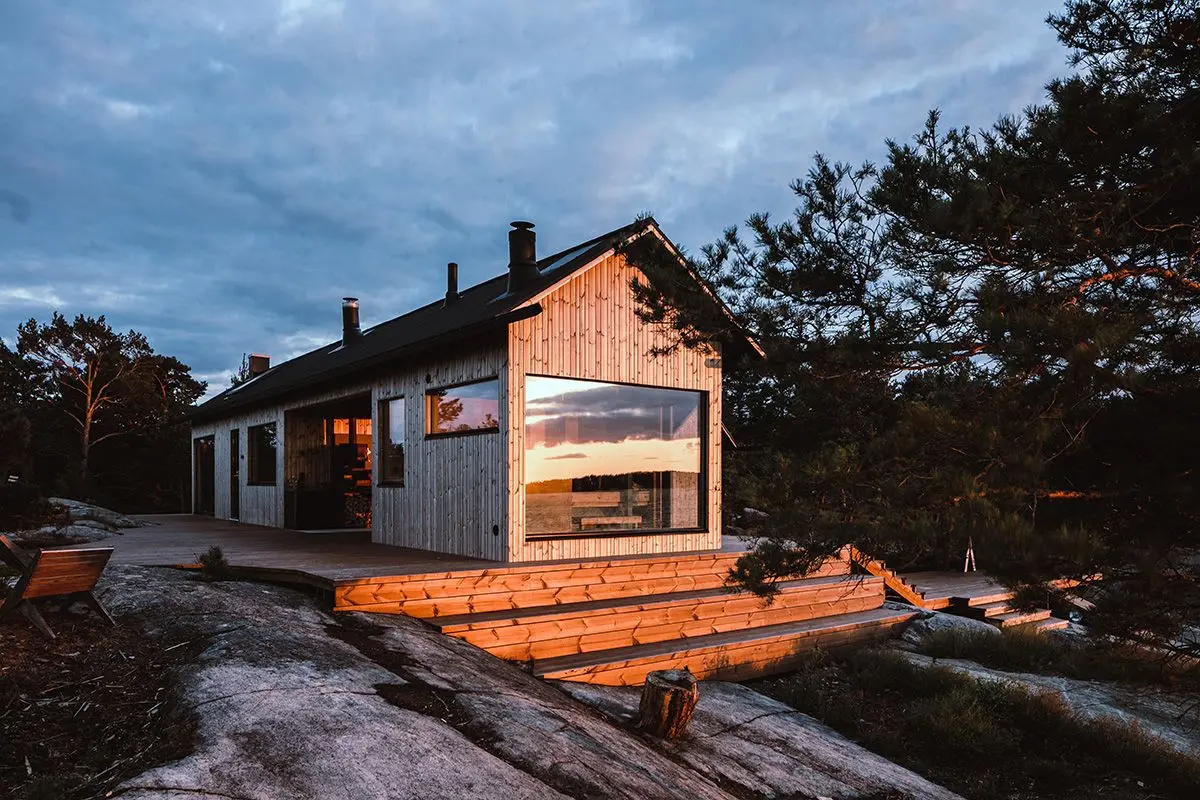 moderne hytte ved sjøen med store vinduer og vedlikeholdsfri kledning.